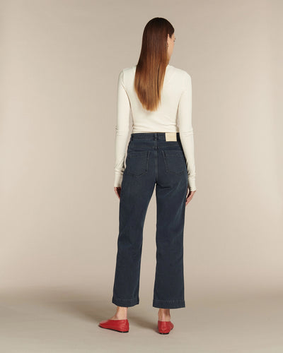 Jean pour femme en denim 100% coton bleu foncé, coupe droite et taille haute, offrant un tombé fluide et s’adaptant à toutes les morphologies.