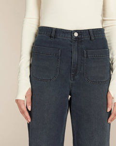 Jean femme en denim 100% coton de couleur bleu foncé avec coupe droite et taille haute, doté de grandes poches plaquées devant pour un style casual et adaptable.