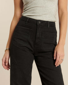 Jean en denim 100% coton de couleur gris très foncé, coupe droite et taille haute, avec grandes poches plaquées sur l'avant pour un style décontracté et moderne.