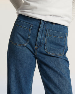 Jean en denim bleu moyen avec coupe droite et poches avant plaquées, conçu pour épouser toutes les morphologies féminines avec confort et élégance.