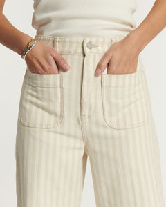 Jean pour femme en denim 100 % coton de couleur sable clair avec rayures subtiles, coupe droite et poches avant larges, offrant un ajustement confortable et moderne.