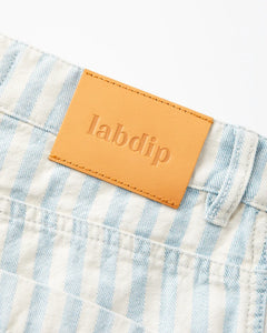 Détail d'un jean en denim rayé bleu clair et blanc en coton avec une étiquette cuir camel embossée Labdip, coupe droite adaptée à toutes morphologies féminines.