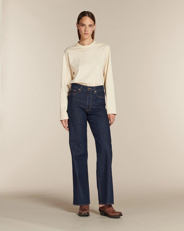 Jean droit long en denim brut 100% coton, taille haute, ajusté à la taille et aux hanches, avec une coupe qui s’adapte aux morphologies en X, V, et H.