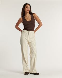 Jean femme en coton beige clair à fines rayures verticales, coupe large et droite, offrant une silhouette fluide et confortable idéale pour l'été.