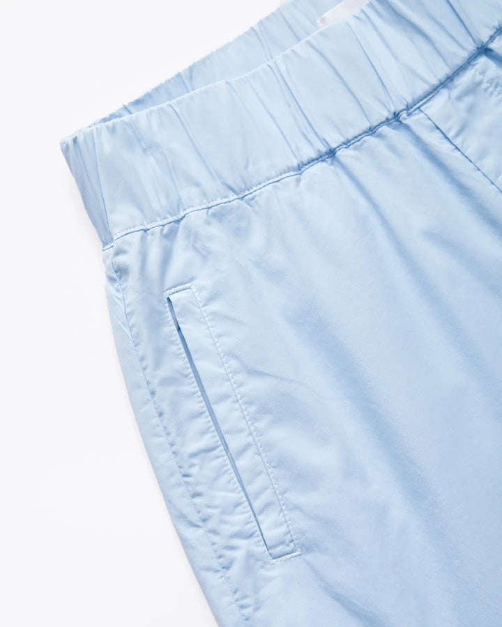 Pantalon femme en popeline bleu clair, coupe droite avec ceinture élastique et poches latérales discrètes, tissu léger adapté pour l'été.